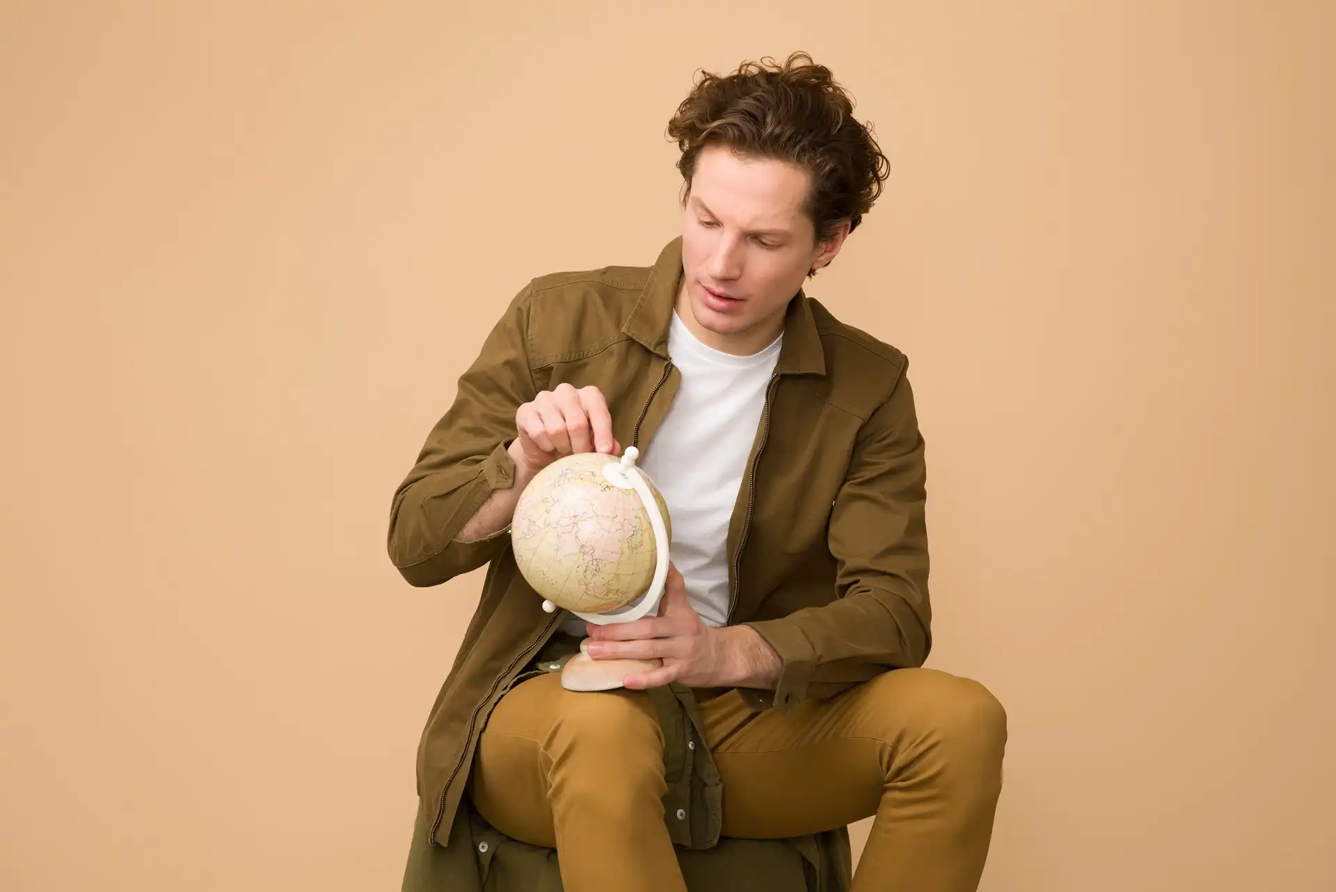 In the picture, a man looking at a globe.